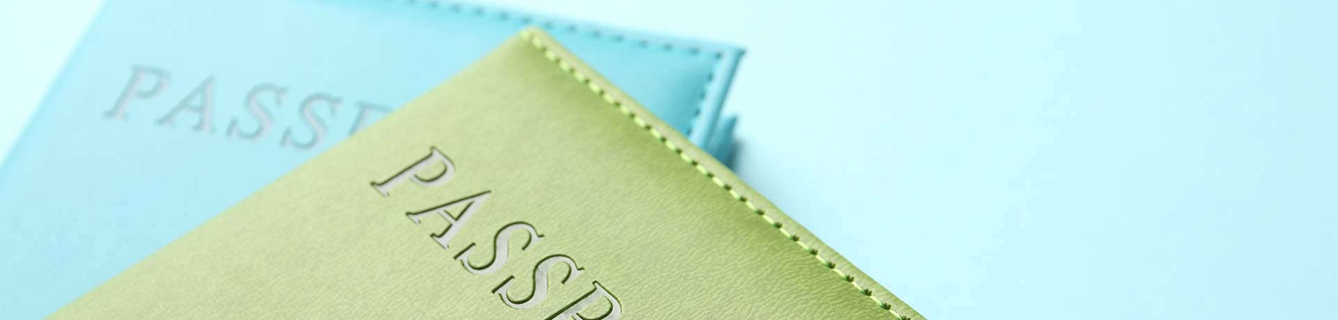 Two passports stacked on a light blue surface, with a lime-green cover in the foreground.